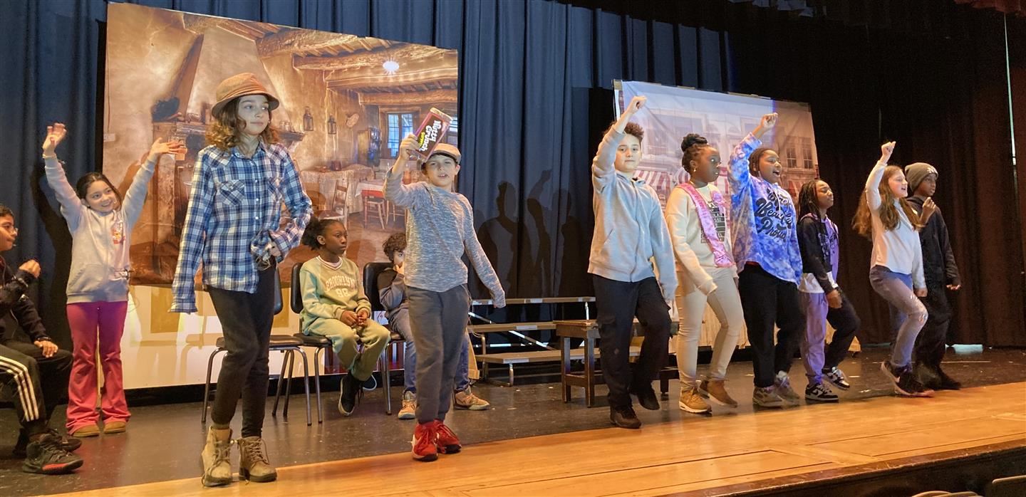 Students in a line march and sing on stage