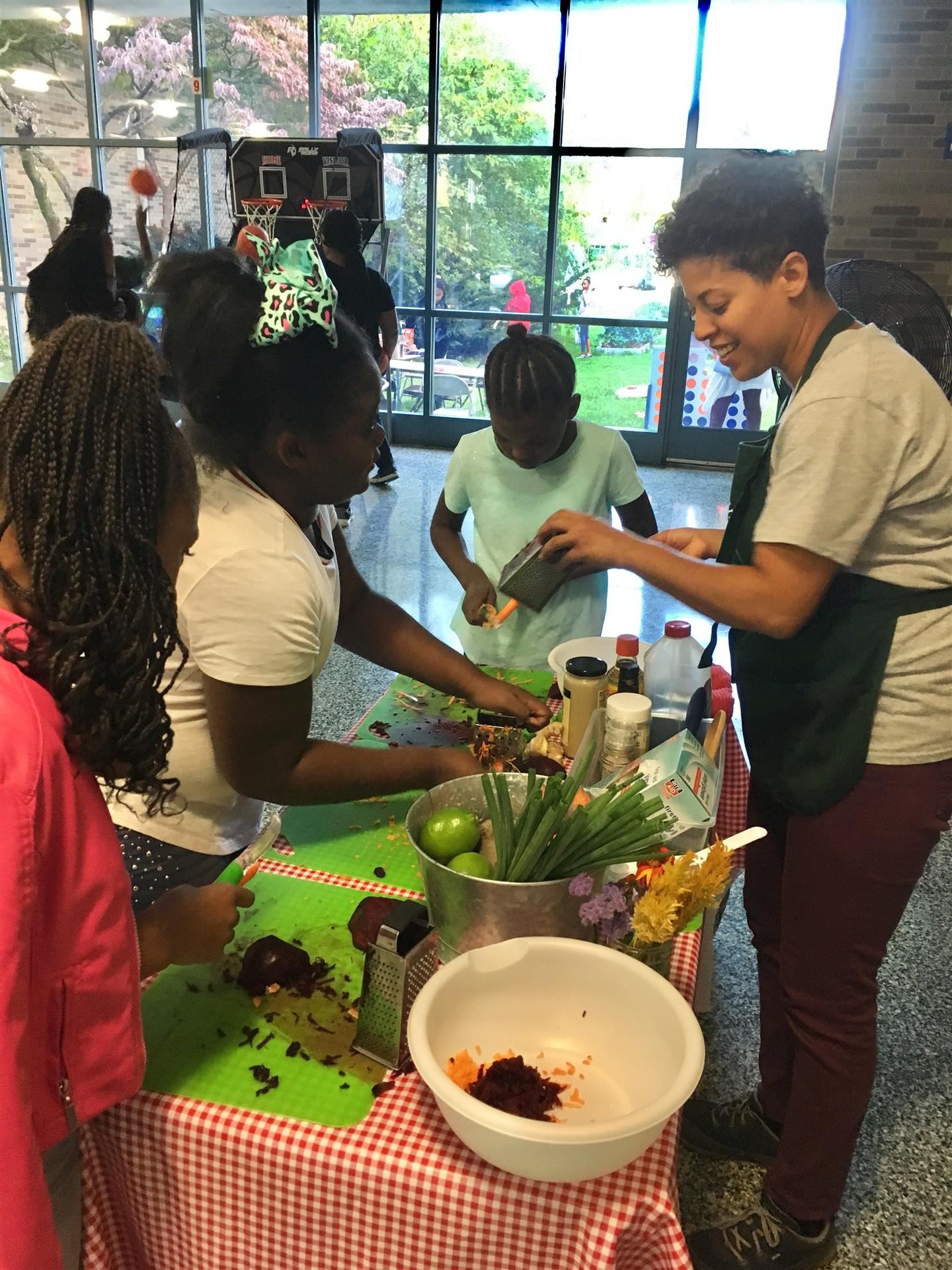 Students surround a table where someone gives a cooking demonstration.