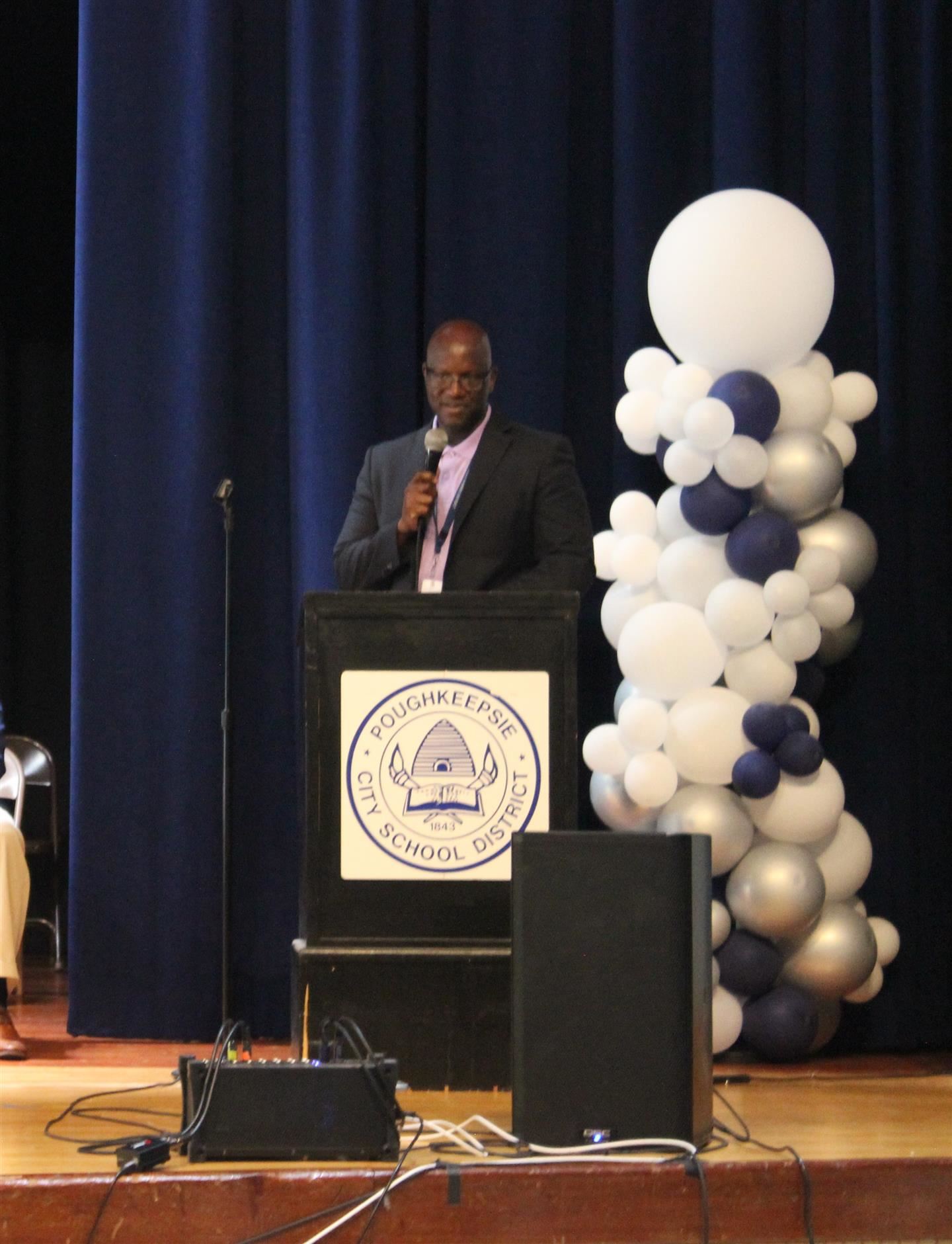 Mr. Gregory Mott speaks at a podium