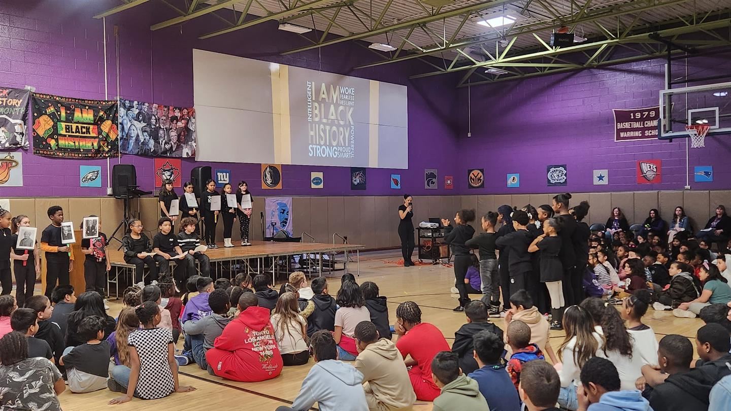  A large number of students watch student performances in a school gym