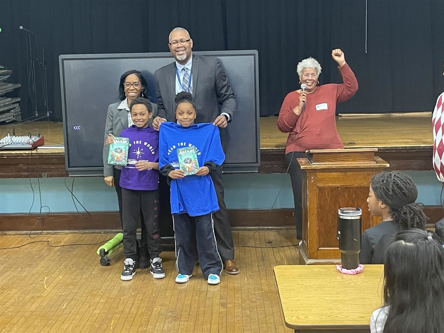  Three adults stand with two student members of the Red The World Program