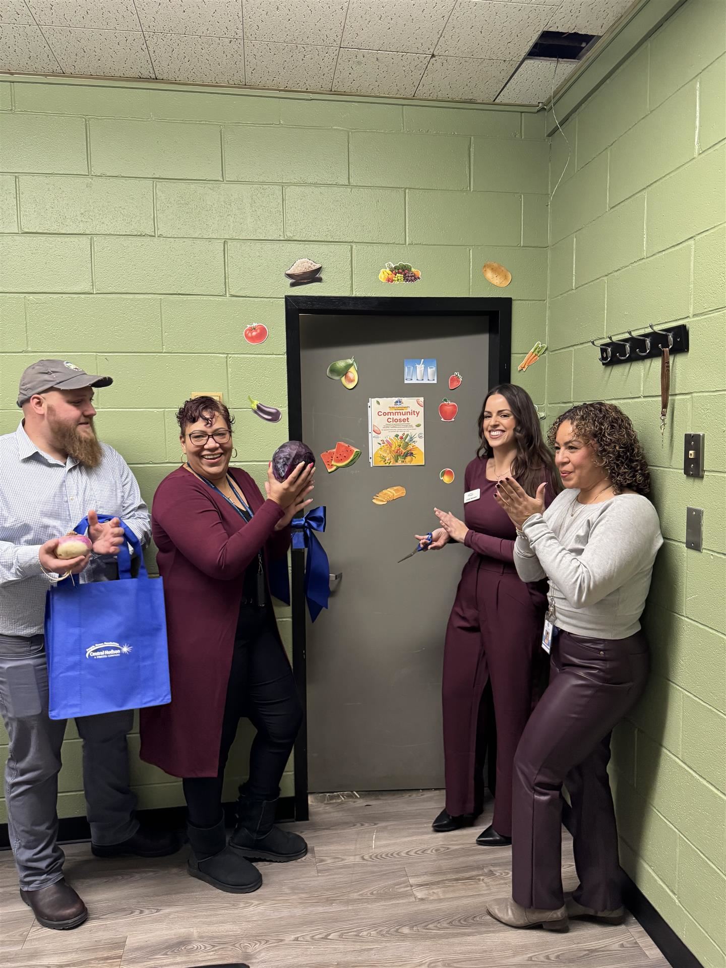  Four people clap outside a door during a ribbon-cutting ceremony