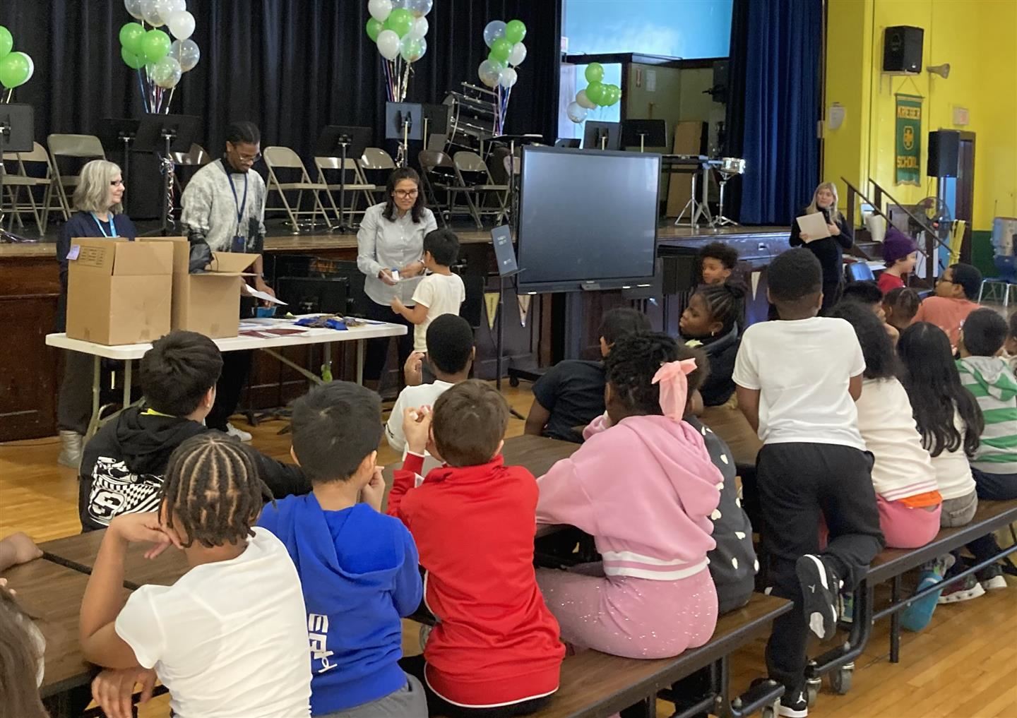  A students gets an award from a school leader as other students look on from a long table