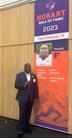  Tyre Coleman stands next to his Hobart College Athletic Hall of Fame induction banner.